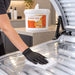 Liquidate® Sunbed & Salon antibacterial wipes in a white 1000-sheet bucket, shown wiping a clear sunbed surface.