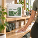 Antibacterial wipe bucket, white plastic with a green label and 500-sheet marking, Liquidate® Yoga & Pilates wipes for studio cleaning.