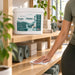 Antibacterial wipe bucket, Liquidate® Yoga & Pilates, white plastic tub with teal branding and 600-sheet label.